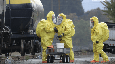 People in hazardous material suits by a truck