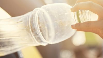 Person's arm putting a plastic bottle into a recycling 