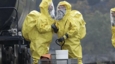 People in hazardous material suits by a truck